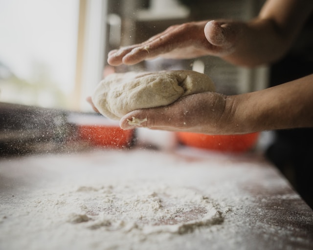 Hands shaping pizza dough